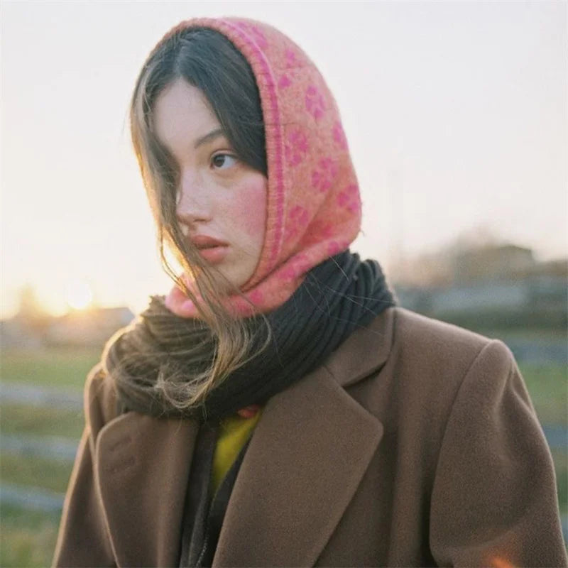 Young woman in a pink headscarf and brown coat showcasing a pink knitted balaclava